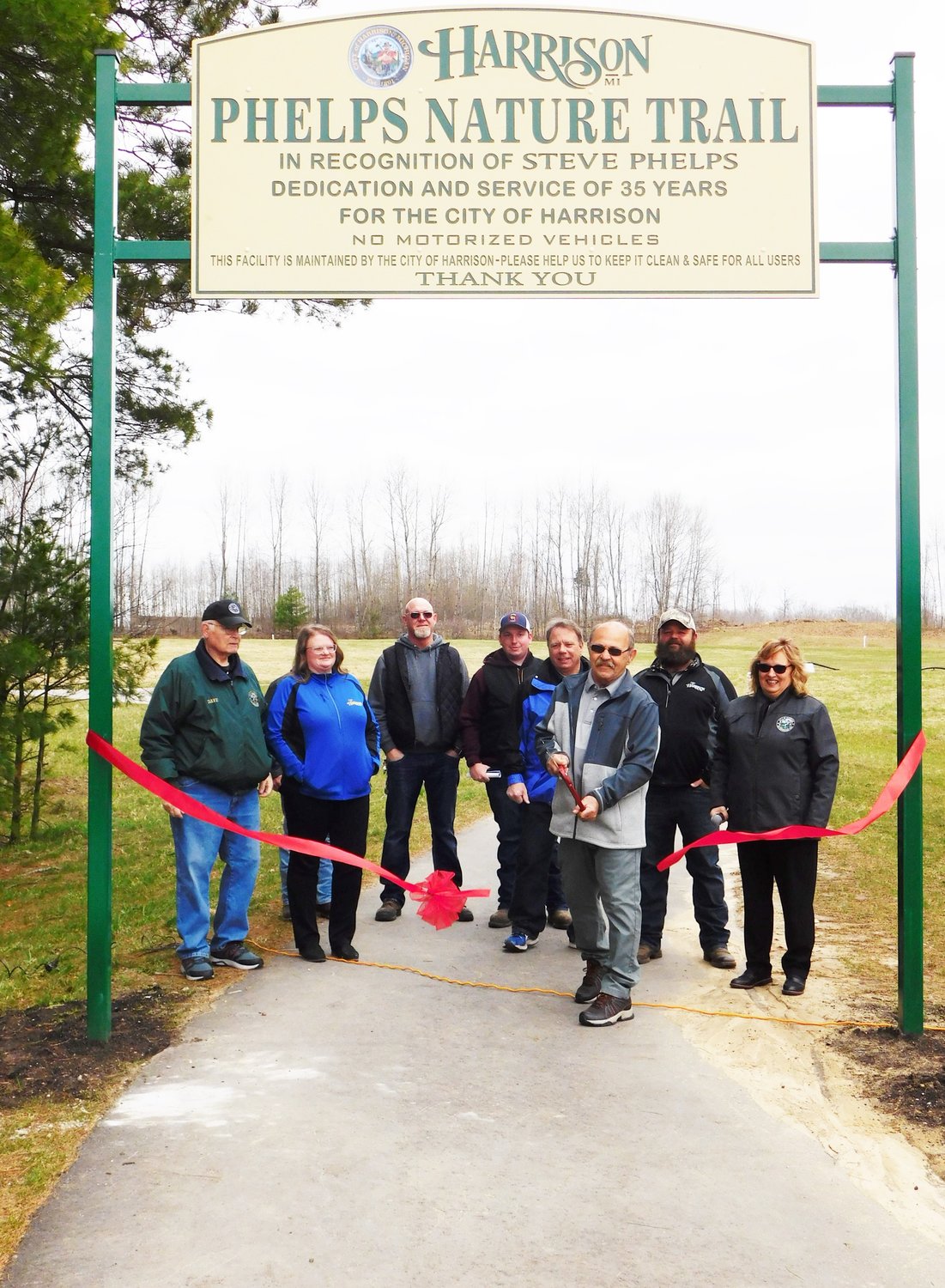 Steve Phelps snips the ribbon, officially opening the nature trail named in his honor. He is flanked, from left, by Council members Dave Rowe and Angela Kellogg, DPW Superintendent Sam Russell, Colton Hilyard, Mayor Pro Tem Dan Sullivan, son Johnny Phelps and retiring Harrison City Manager Tracey Connelly.